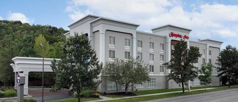 A Hampton Inn hotel with a modern design, featuring a two-story structure and a parking lot in front.