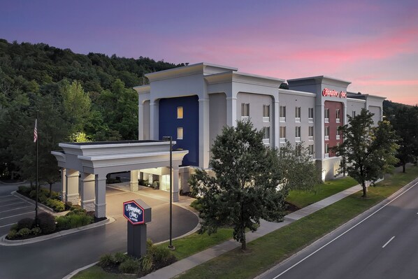 A Hampton Inn hotel with a modern design, featuring a blue and white facade, a well-maintained lawn, and a parking lot.