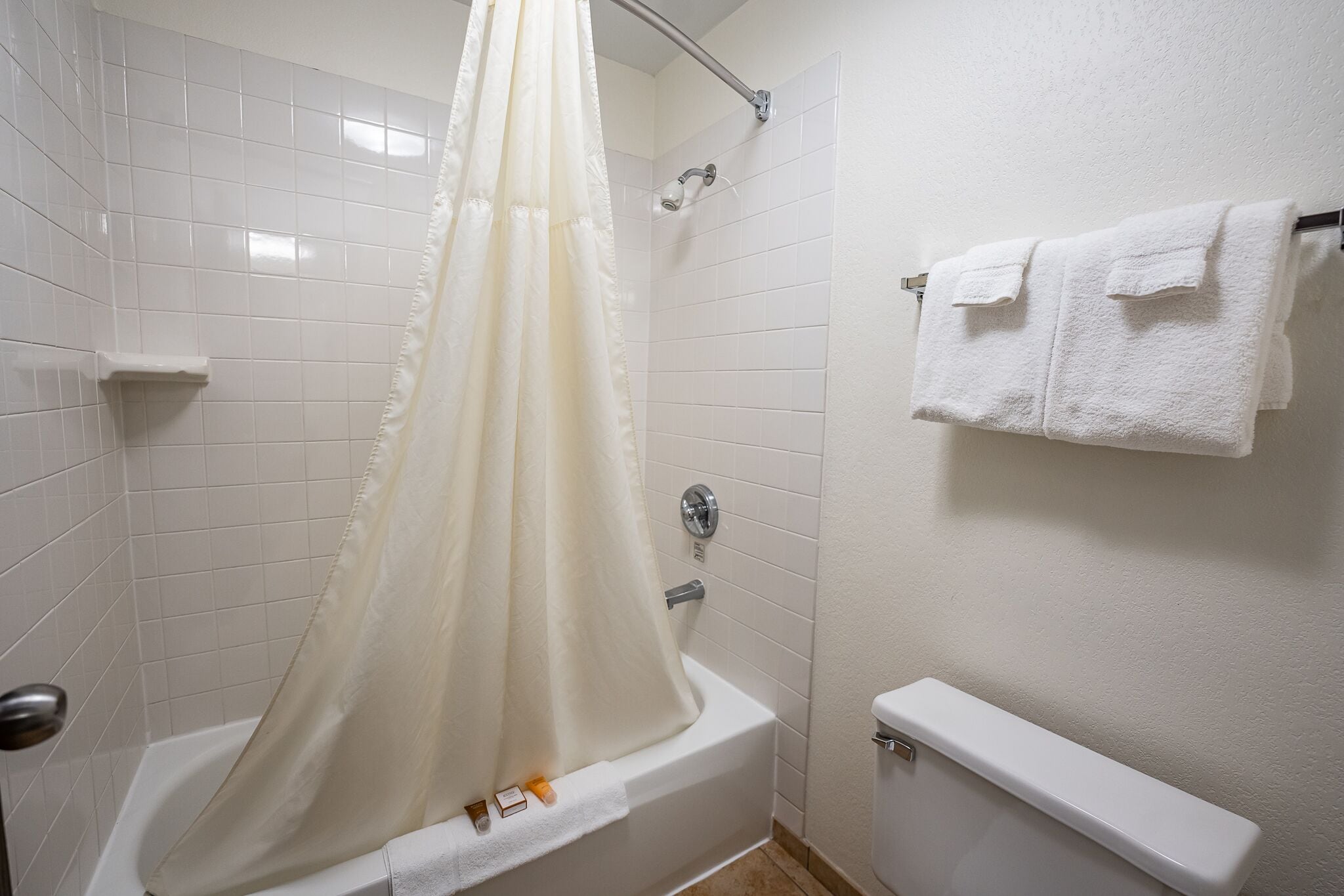 Une salle de bain avec une baignoire, un rideau de douche, un porte-serviettes avec deux serviettes et des toilettes.