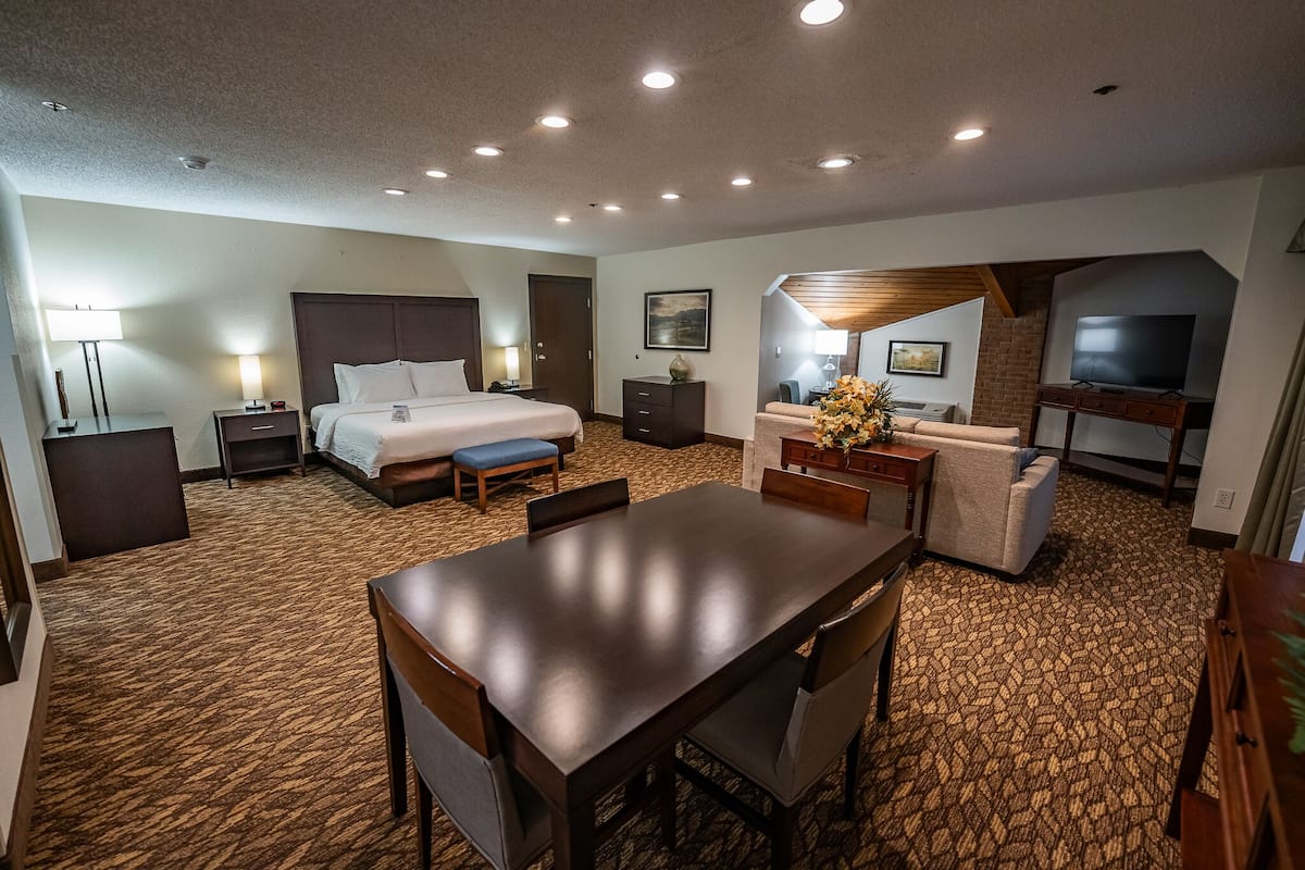 Quarto de hotel com uma cama grande, uma escrivaninha, um sofá e uma televisão.