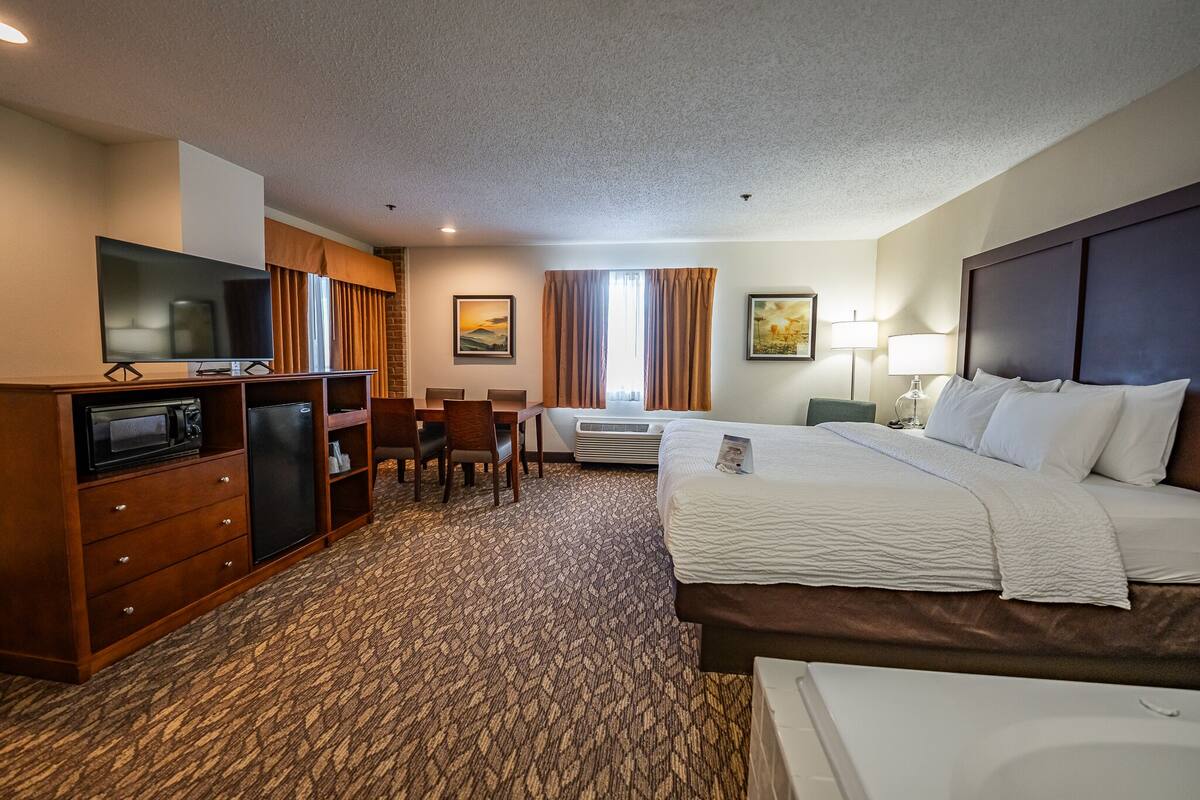 Quarto de hotel com cama, escrivaninha, televisão, mini-geladeira e micro-ondas.