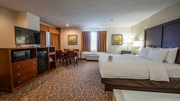 A hotel room with a bed, a desk with a TV, a mini-fridge, and a microwave.