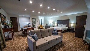 Ein Hotelzimmer mit einer Couch, einem Bett, einem Schreibtisch und einem Stuhl.
