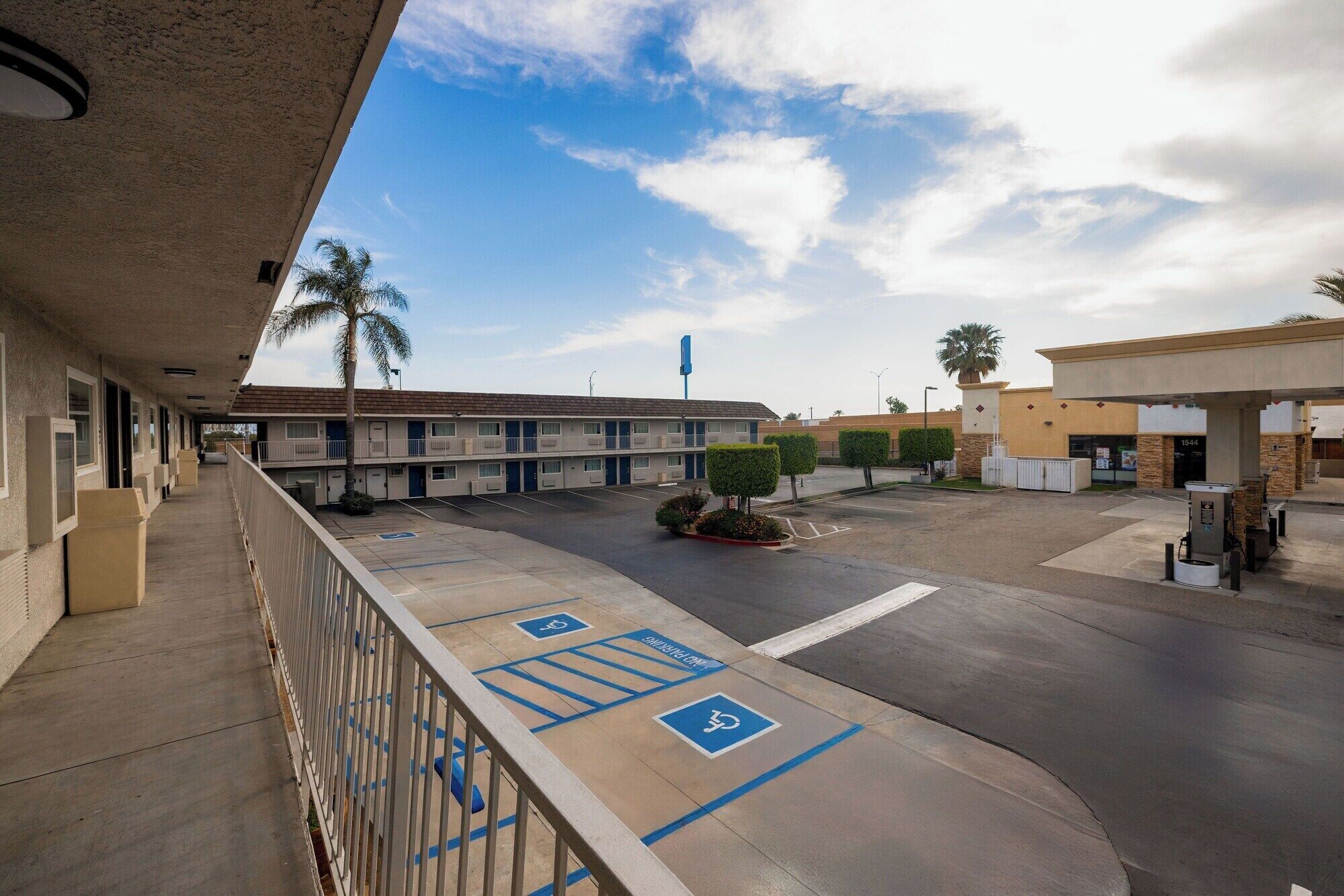 A motel with a covered parking area, a gas station, and a clear sky.