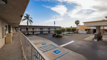 A motel with a covered parking area, a gas station, and a clear sky.