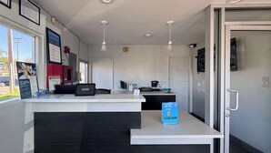 Un espace d’accueil comprenant un comptoir, un ordinateur, un téléphone et un panneau bleu.