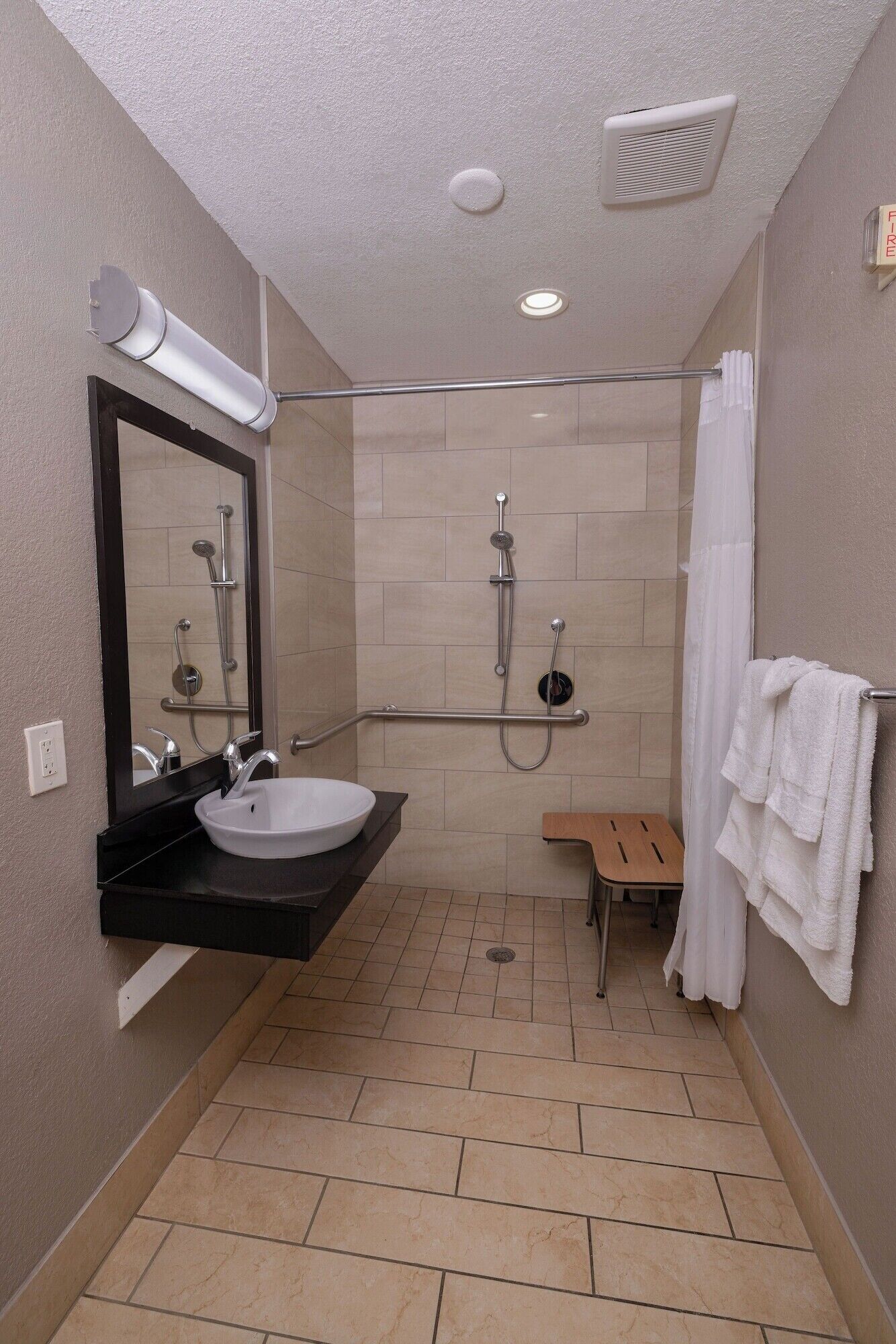 Un baño moderno con ducha, lavamanos, espejo y toallero.