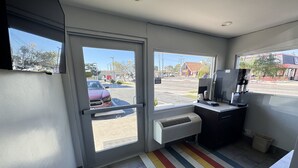 Une petite pièce, bien éclairée, avec une grande fenêtre, une porte et un tapis rayé aux couleurs vives.