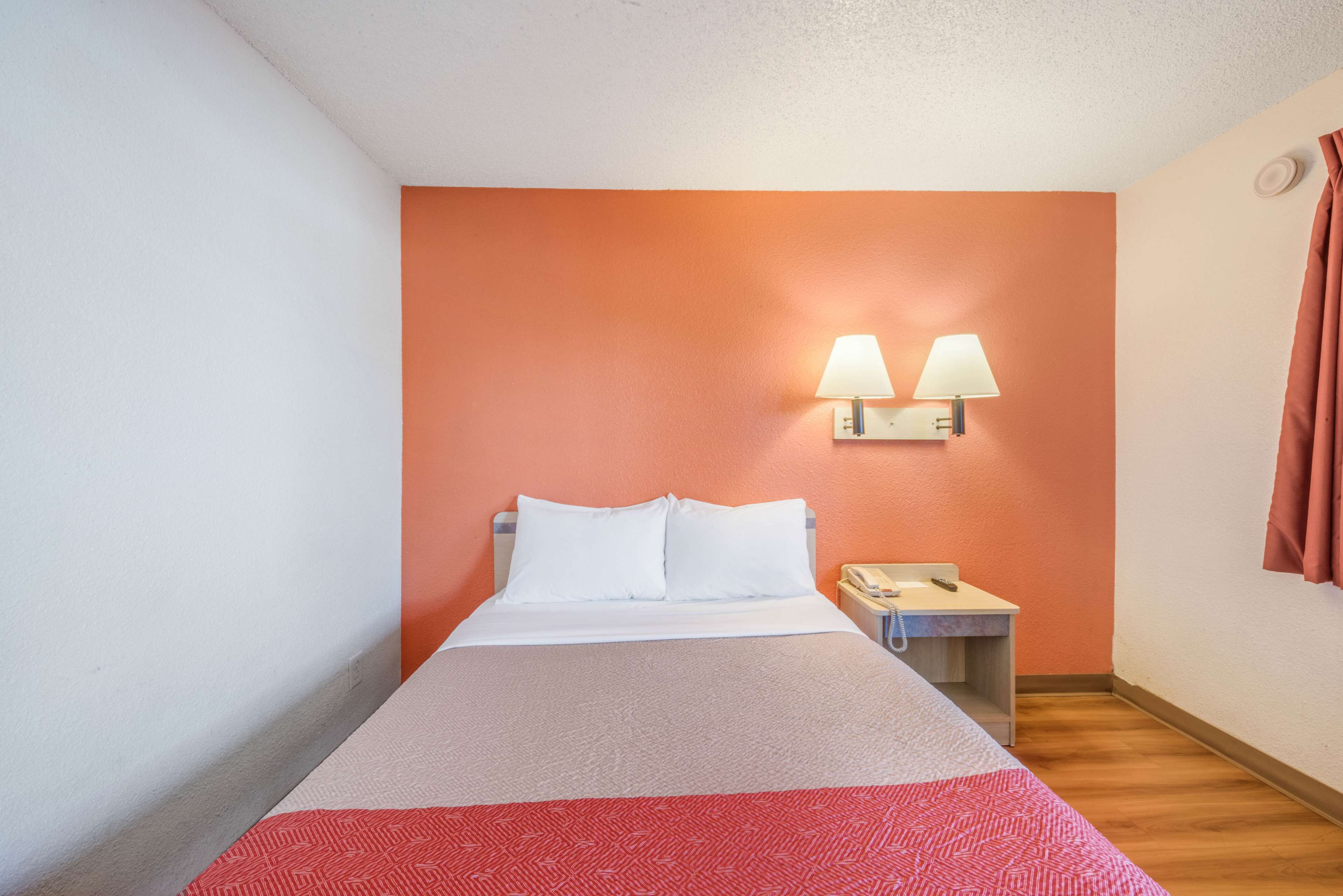 Une chambre d’hôtel avec un lit, deux lampes de chevet, une table de chevet et un téléphone.