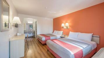 Una habitación de hotel con dos camas, un escritorio y un espejo.