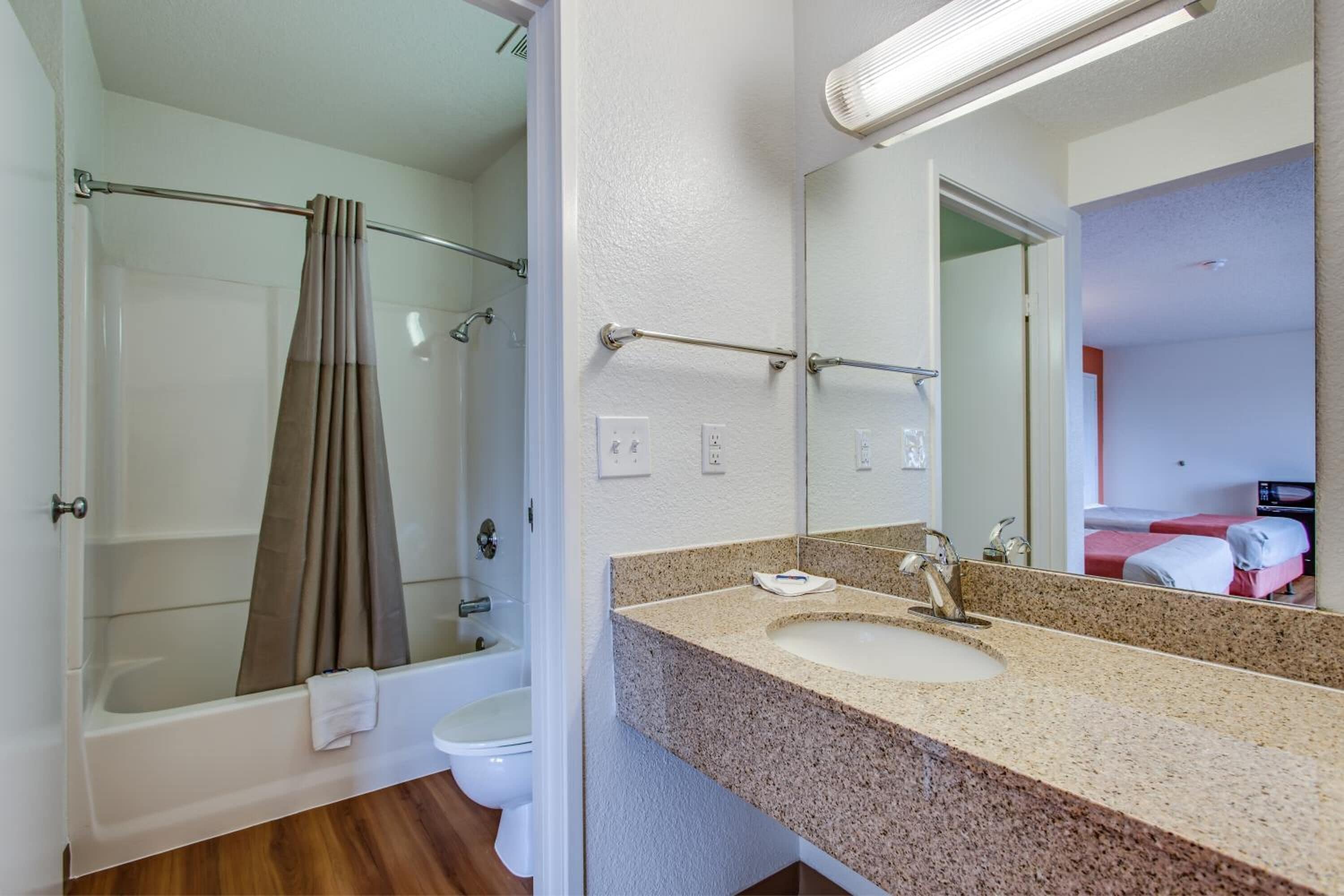 A bathroom with a bathtub, a toilet, a sink with a mirror, and a shower curtain.
