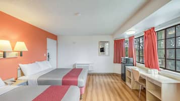 A hotel room with two beds, a desk, a chair, a TV, and a window with curtains.