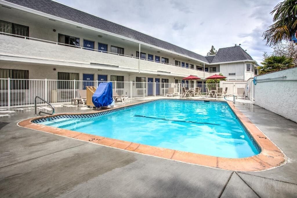 Una piscina rectangular con borde azul, rodeada por una terraza de hormigón.
