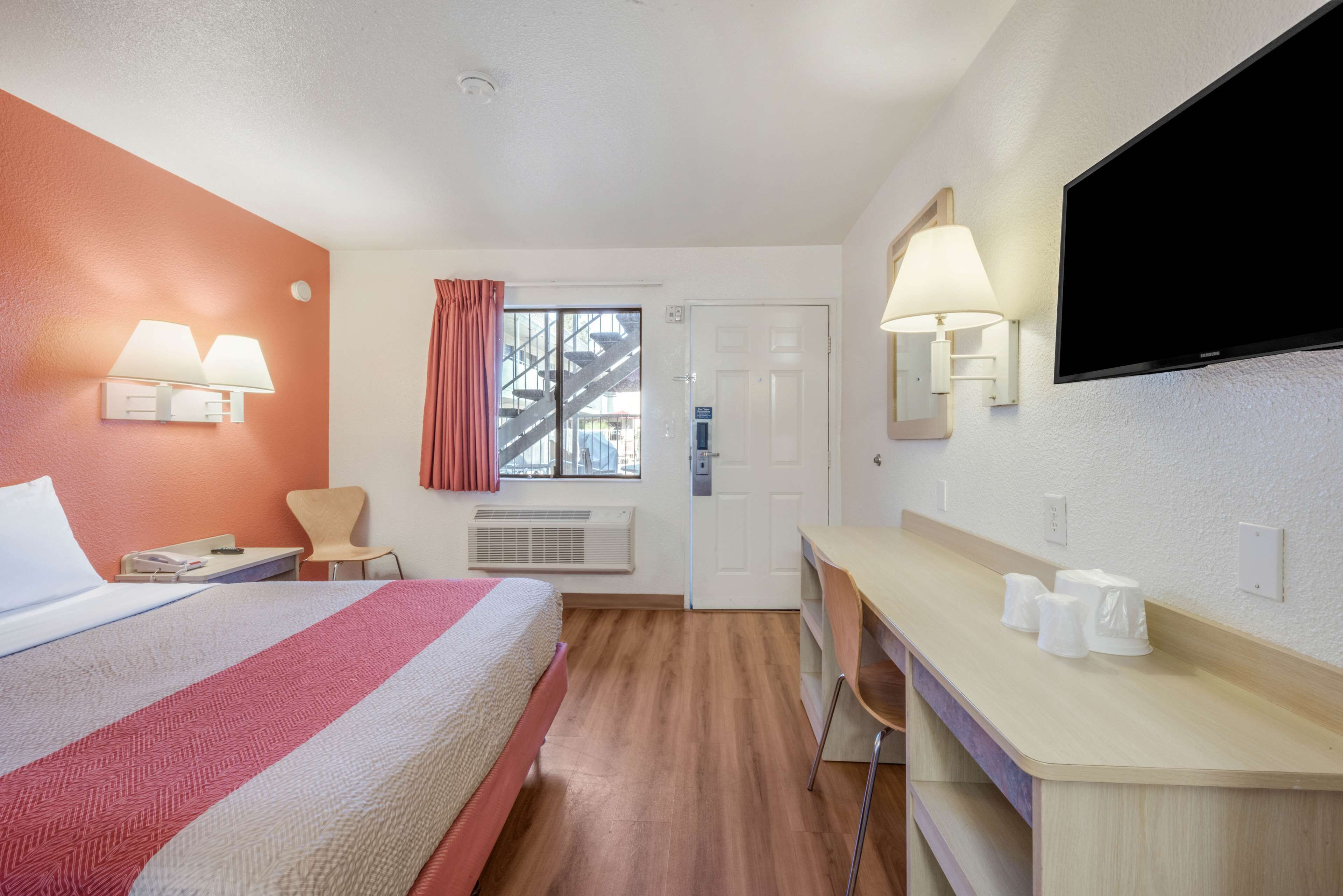 A hotel room with a bed, desk, chair, and TV.