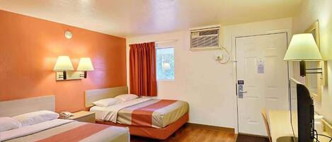 Una camera d'albergo con due letti, una scrivania con un computer, una finestra con tende e una porta con un cartello.