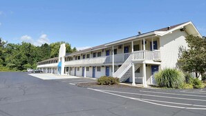 Un motel con escaleras centrales, varias habitaciones y un estacionamiento.