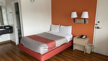 A hotel room with a bed, bedside table, and a bathroom visible through an open door.