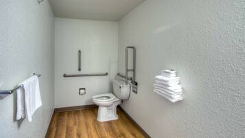 Un baño pequeño y estrecho con inodoro blanco, barandilla y perchero.