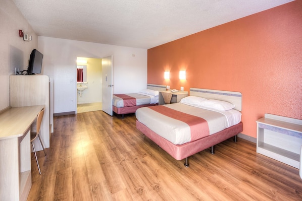 Habitación de hotel con dos camas, un escritorio y un televisor.