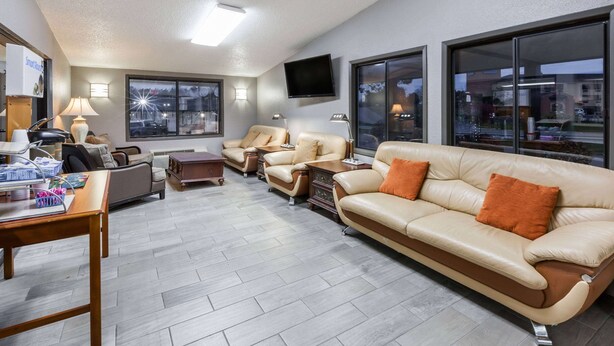 Un salon moderne avec un canapé, des fauteuils, une table basse et un téléviseur fixé au mur.