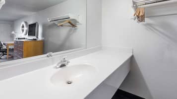 A modern bathroom with a large mirror, a white sink, and a towel rack.