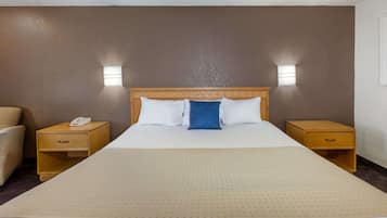 Une chambre d’hôtel avec un grand lit, deux tables de chevet, une petite table et une chaise.