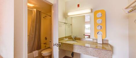A bathroom with a shower, toilet, sink, and mirror.
