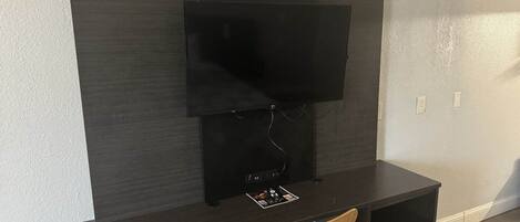 A modern entertainment unit with a flat-screen TV, a coffee machine, and a wooden chair.