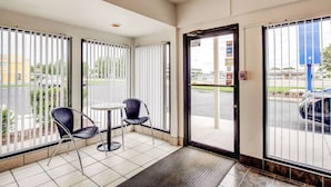 A hotel entrance with a glass door, a small table, and two chairs. - Travelodge by Wyndham Norfolk Airport (Norfolk)