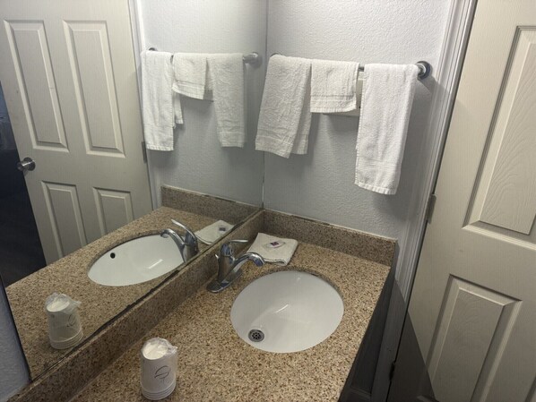 A bathroom with two sinks, a mirror, and towels hanging on the wall.