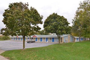 A motel with multiple rooms, a parking lot, and a grassy area with trees. - Americas Best Value Inn & Suites Jackson, MI (Jackson)