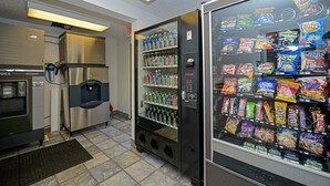 A hotel room with a minibar, a refrigerator, and a vending machine stocked with snacks and beverages. - Americas Best Value Inn & Suites Jackson, MI (Jackson)