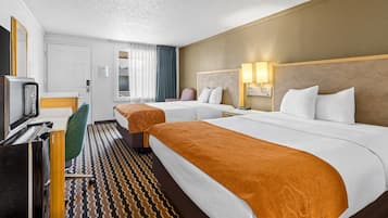 A hotel room with two beds, a desk with a computer, a chair, and a television.