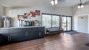 Une cuisine moderne dotée d’une machine à expresso intégrée, d’une grande fenêtre avec stores, d’un banc et d’un ventilateur de plafond.