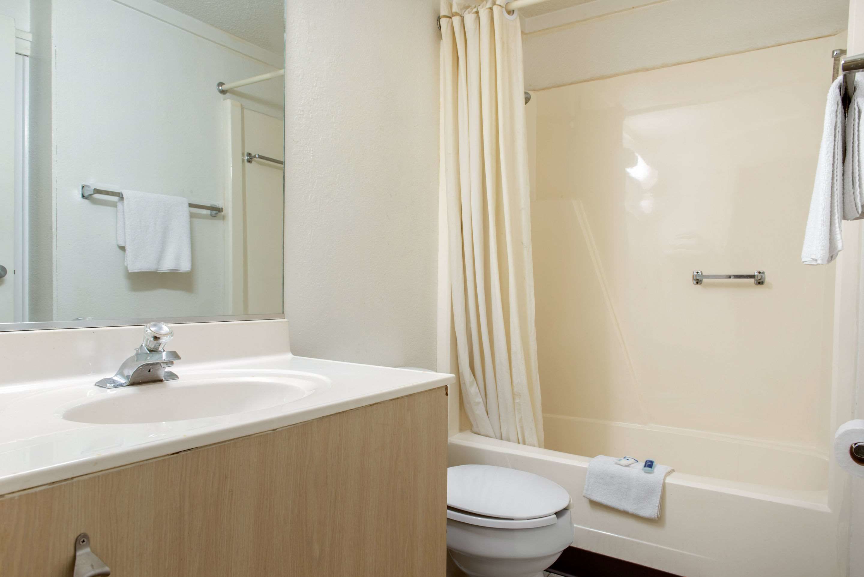 A bathroom with a sink, mirror, toilet, and bathtub.
