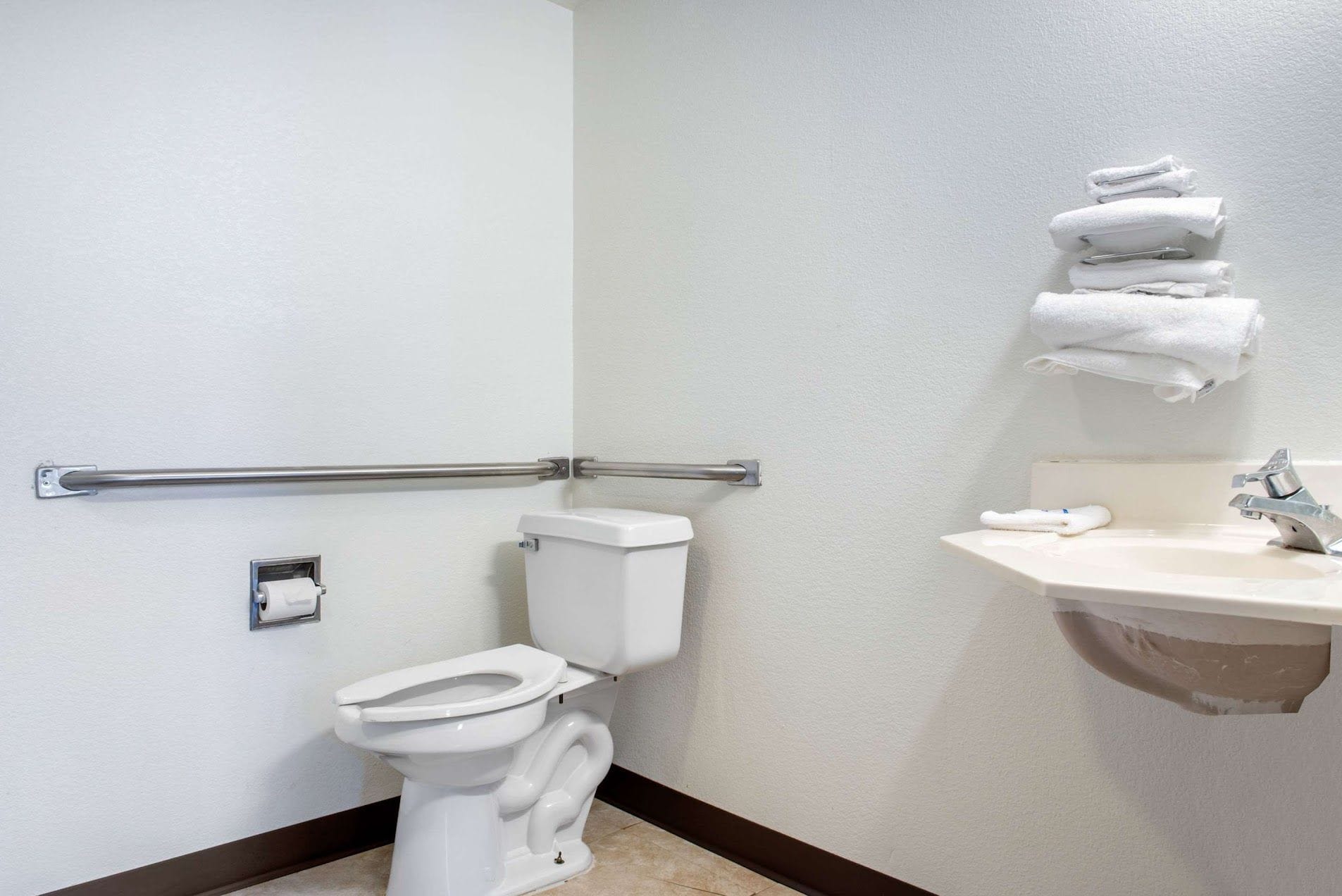 Un baño con inodoro, lavamanos y toallero.
