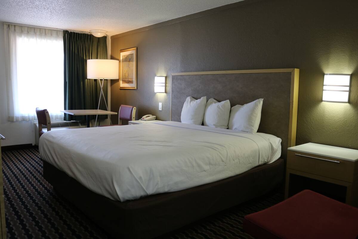 Habitación de hotel con una cama grande, mesitas de noche, un escritorio y una silla.