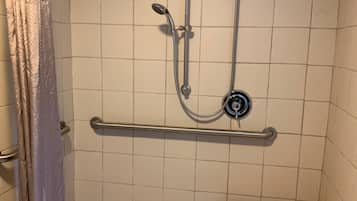 A small, enclosed shower area with a grab bar, a wooden bench, and a showerhead.
