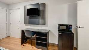 A compact room with a desk, a chair, a flat-screen TV mounted on the wall, and a microwave on a small cabinet. - Motel 6 Laredo, TX - North I-35 (Laredo)