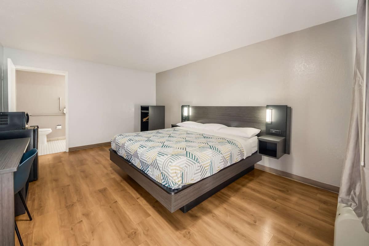 A bedroom with a bed, bedside tables, a desk, and a chair.