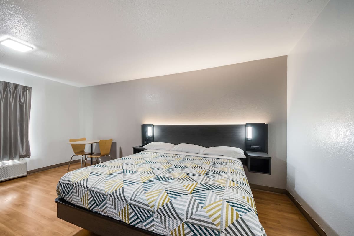 A modern hotel room with a large bed, a desk, and a chair.