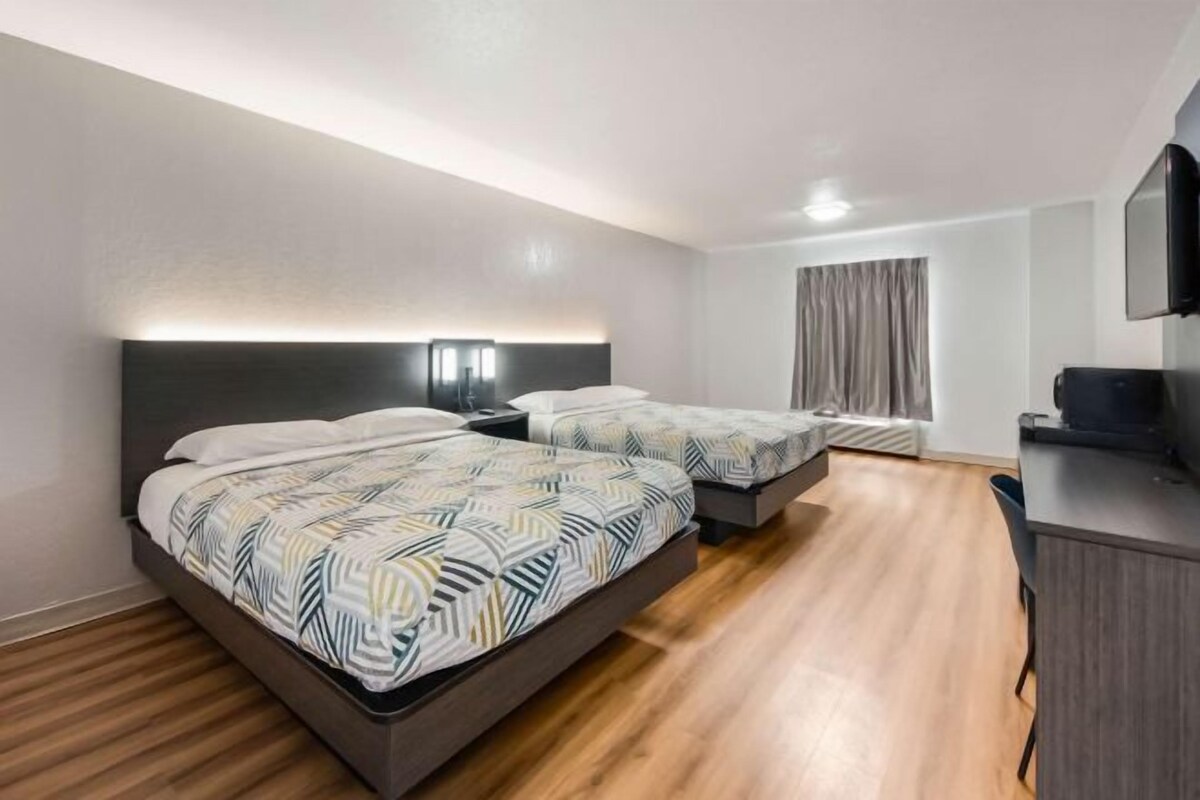 Une chambre d’hôtel avec deux lits, un bureau et une télévision.