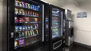 Two self-service beverage vending machines with a variety of snacks and drinks. - Travelodge by Wyndham Madison Heights MI (Madison Heights)