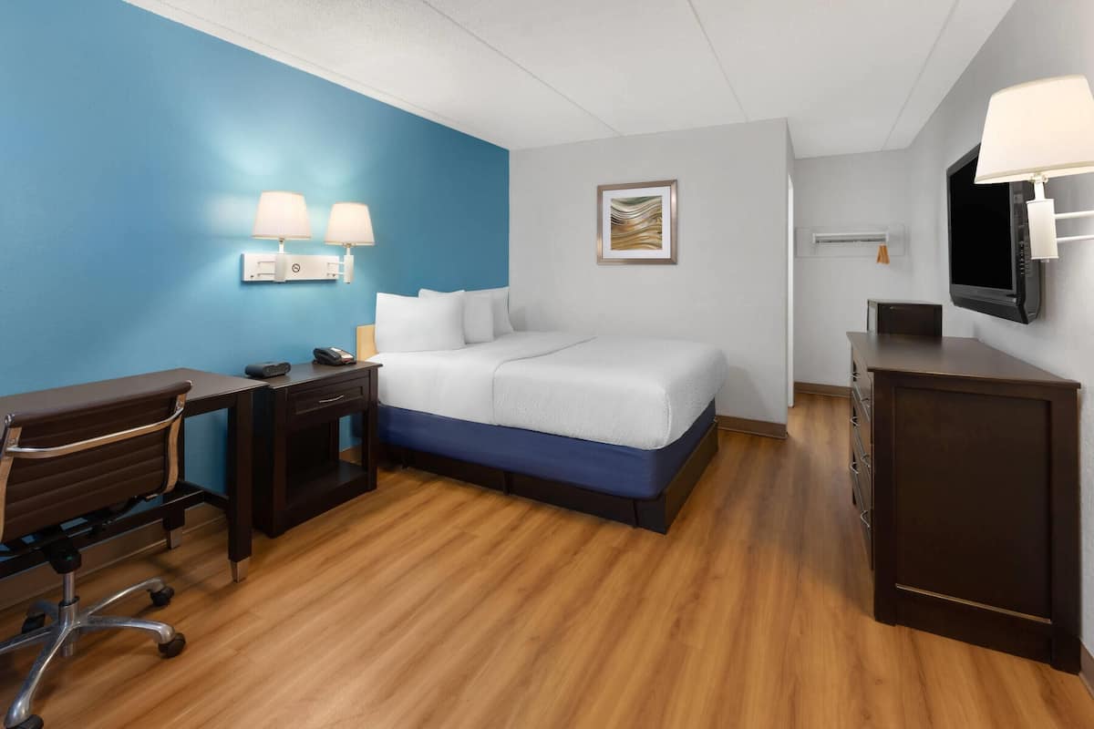 Una habitación de hotel con cama, escritorio, silla y televisión.