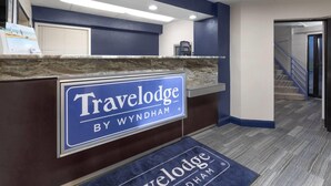 A reception desk with a sign reading "Travelodge by Wyndham". - Travelodge by Wyndham Madison Heights MI (Madison Heights)
