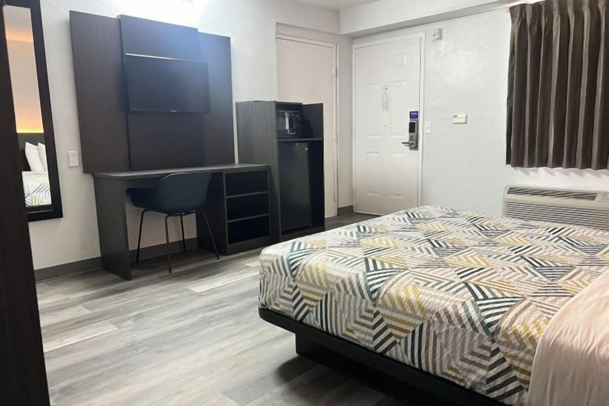 A bedroom with a bed, a desk, a chair, a wardrobe, and a door.