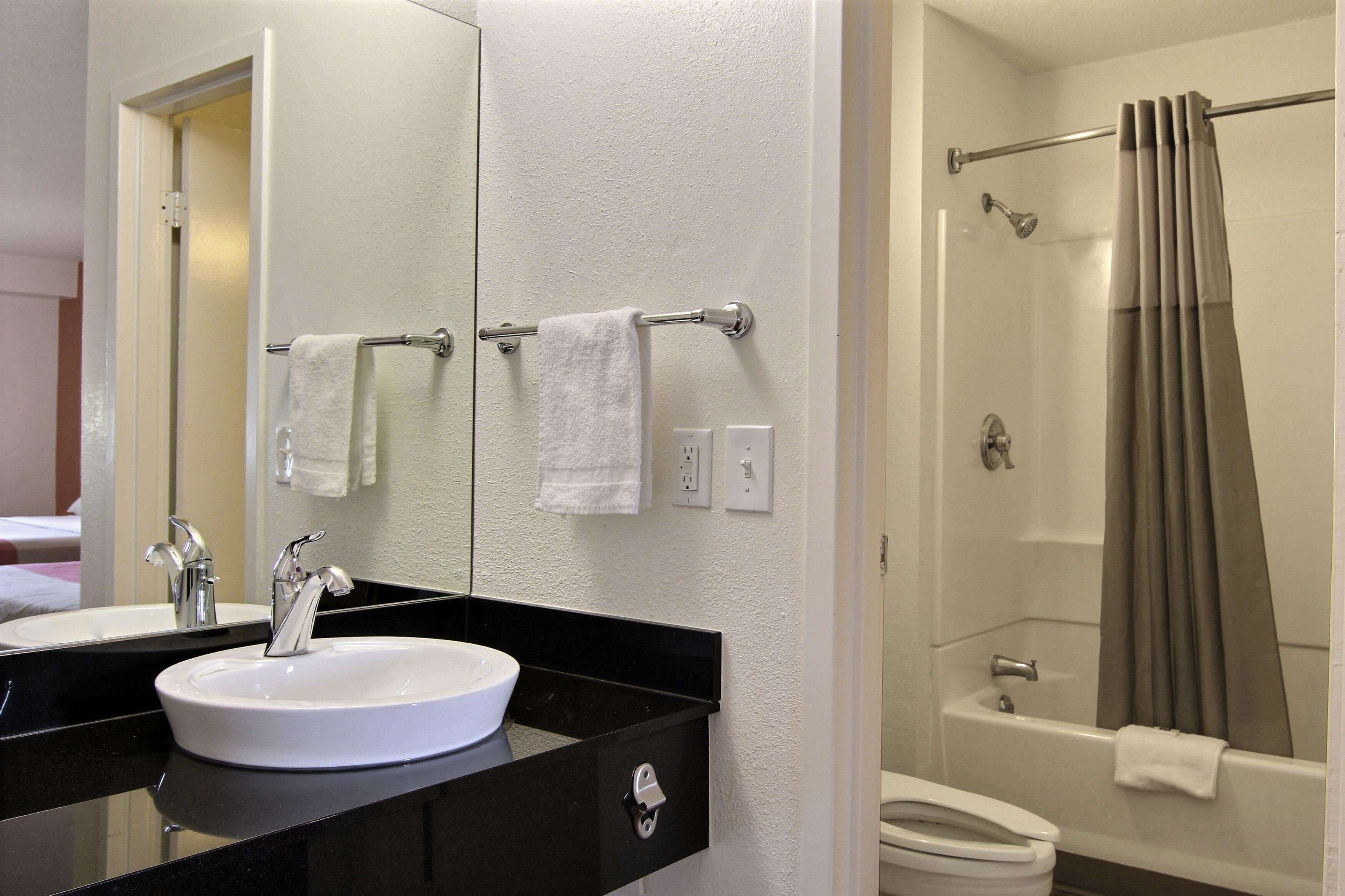 A bathroom with a sink, mirror, towel rack, and shower.