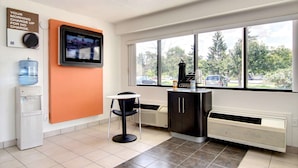 A room with a large window, a water dispenser, a coffee machine, and a television mounted on the wall. - Motel 6 Middleburg Heights, OH - Cleveland (Middleburg Heights)
