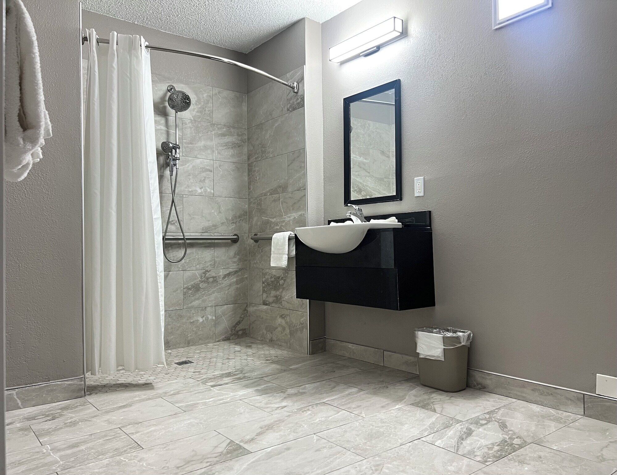 Une salle de bain avec une douche, un lavabo et un miroir.