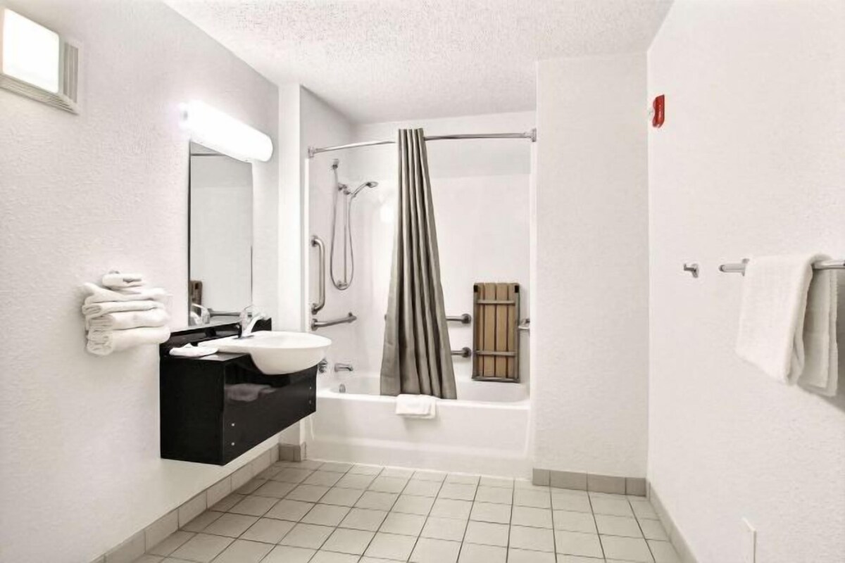 Une salle de bain moderne avec un lavabo blanc, un meuble-lavabo noir et une zone de douche séparée.